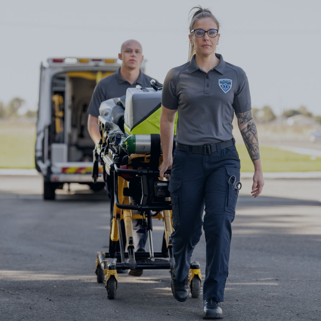 Two EMS professionals pulling a cart with medical supplies.