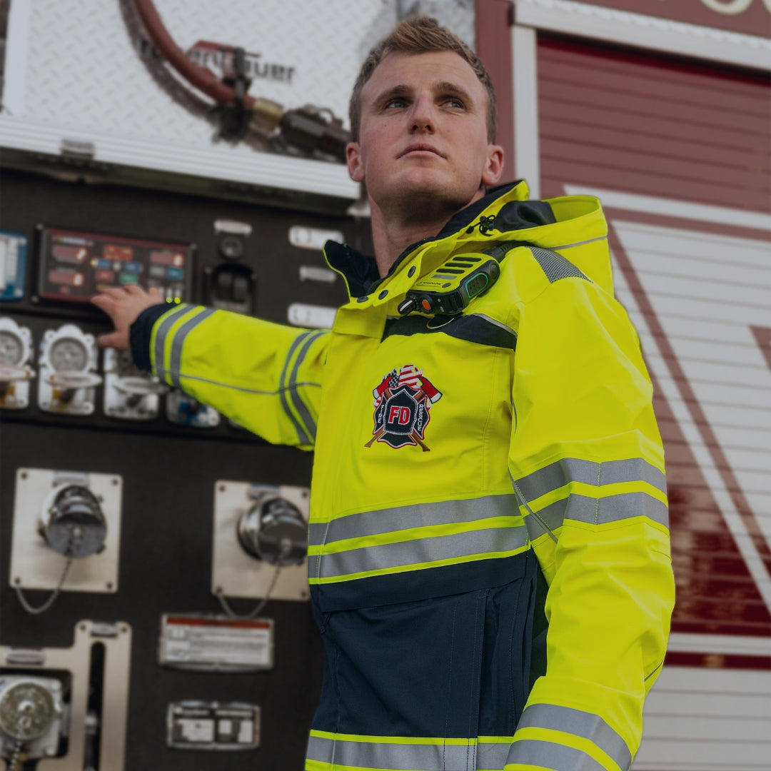 A firefighter wearing a hi-vis parka while operating machinery on a fire truck.