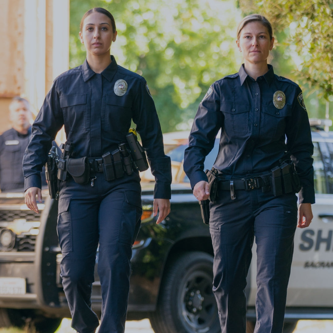Two police officers in full midnight navy uniform.